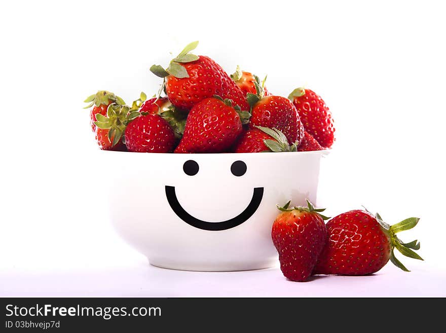 View of a smiley bowl filled with strawberries isolated on a white background. View of a smiley bowl filled with strawberries isolated on a white background.