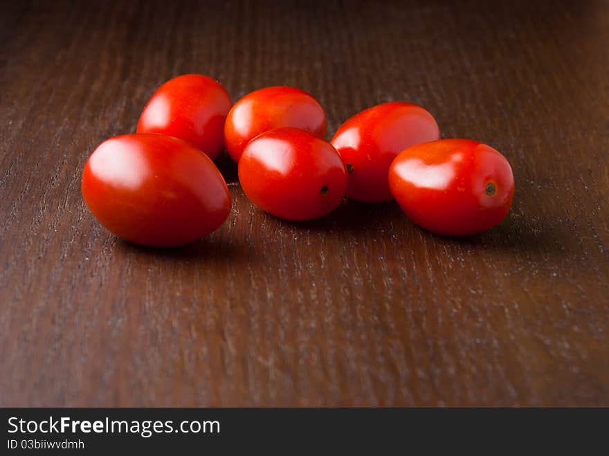 Six red fresh Cherry tomatoes on a wood table. Six red fresh Cherry tomatoes on a wood table