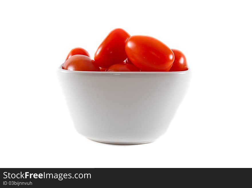 A white bowl of fresh red cherry tomatoes on a white isolated background. A white bowl of fresh red cherry tomatoes on a white isolated background.