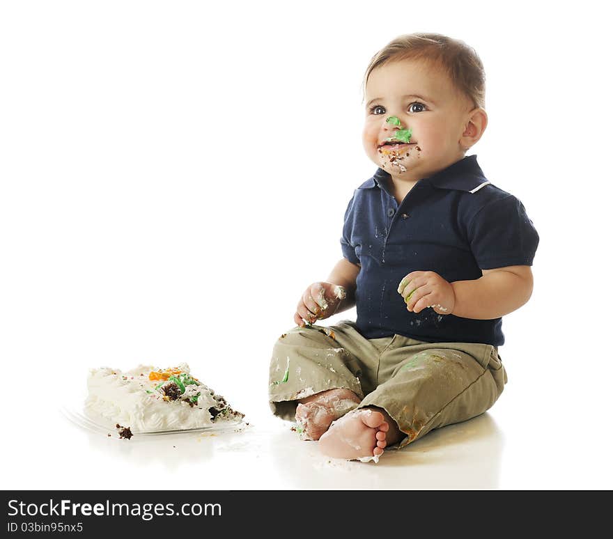 An adorable baby boy happyily digging into a small cake. Isolated on wite. An adorable baby boy happyily digging into a small cake. Isolated on wite.