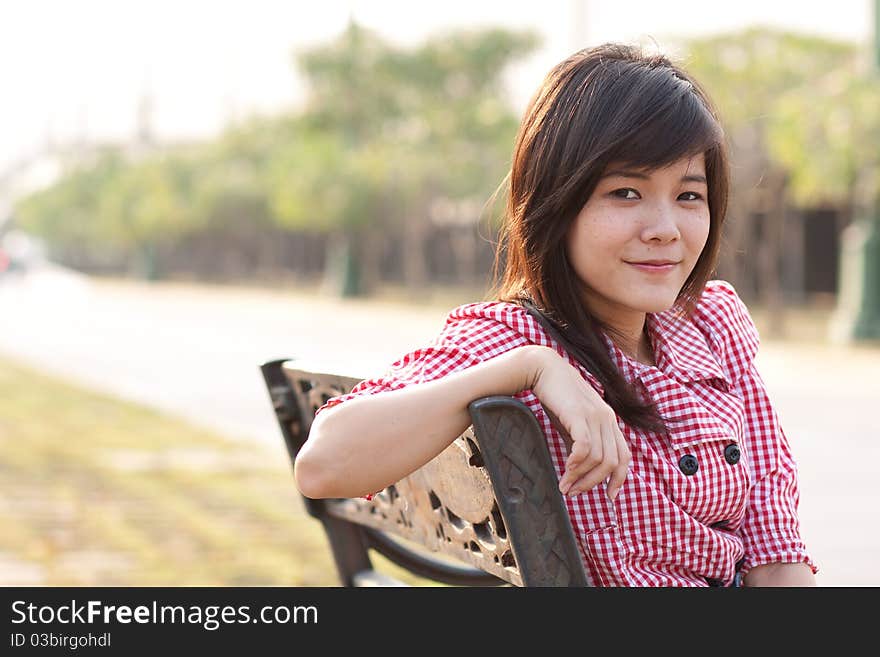 A woman sitting on the bench. On the street. During the evening hours.