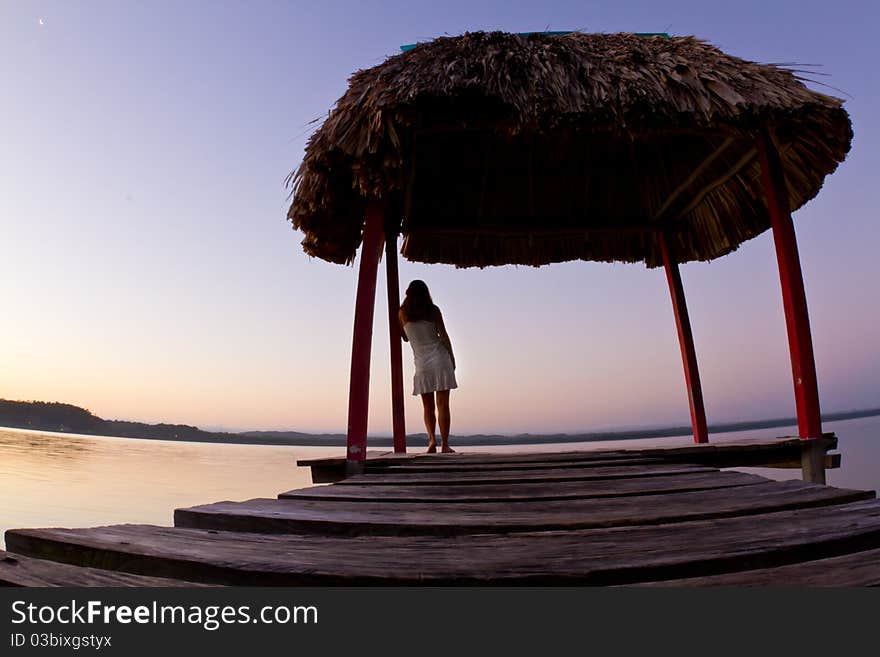 A beautiful girl enjoys Guatemalan sunrise on a wharf at lake Peten. A beautiful girl enjoys Guatemalan sunrise on a wharf at lake Peten.