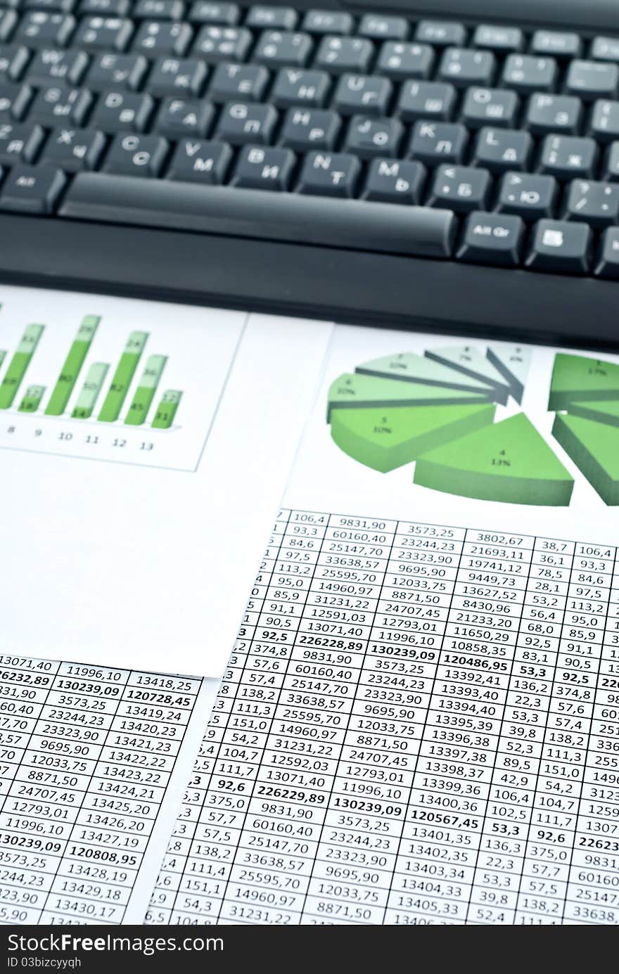 Black keyboard on a stock chart and numbers. Studio shot. Black keyboard on a stock chart and numbers. Studio shot