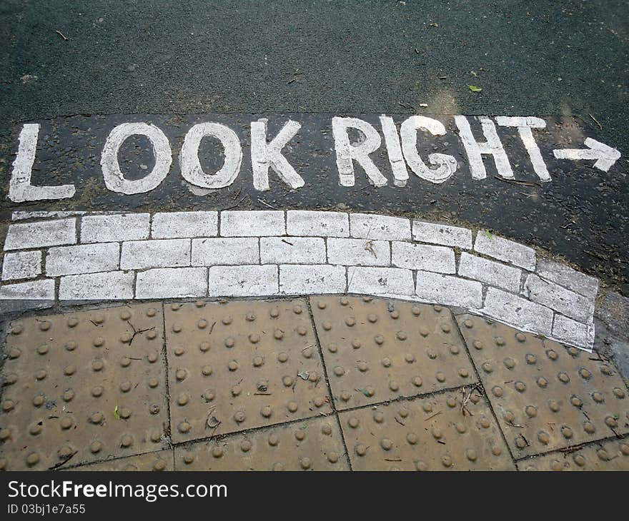 Painted white road sign, reminding pedestrians to look right before crossing the road. Painted white road sign, reminding pedestrians to look right before crossing the road.