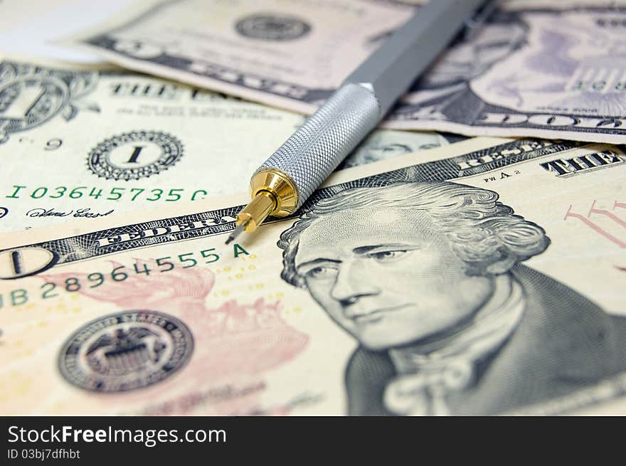 Close-up of US dollar bills ans steel pencil. Differential focus on the barrel of the pencil. Close-up of US dollar bills ans steel pencil. Differential focus on the barrel of the pencil.