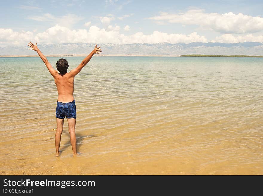 A young happy man raising hands on a beach. A young happy man raising hands on a beach