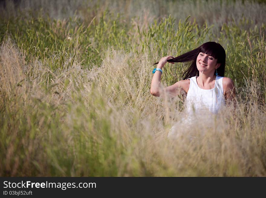 Happy girl in the grass touching her hair