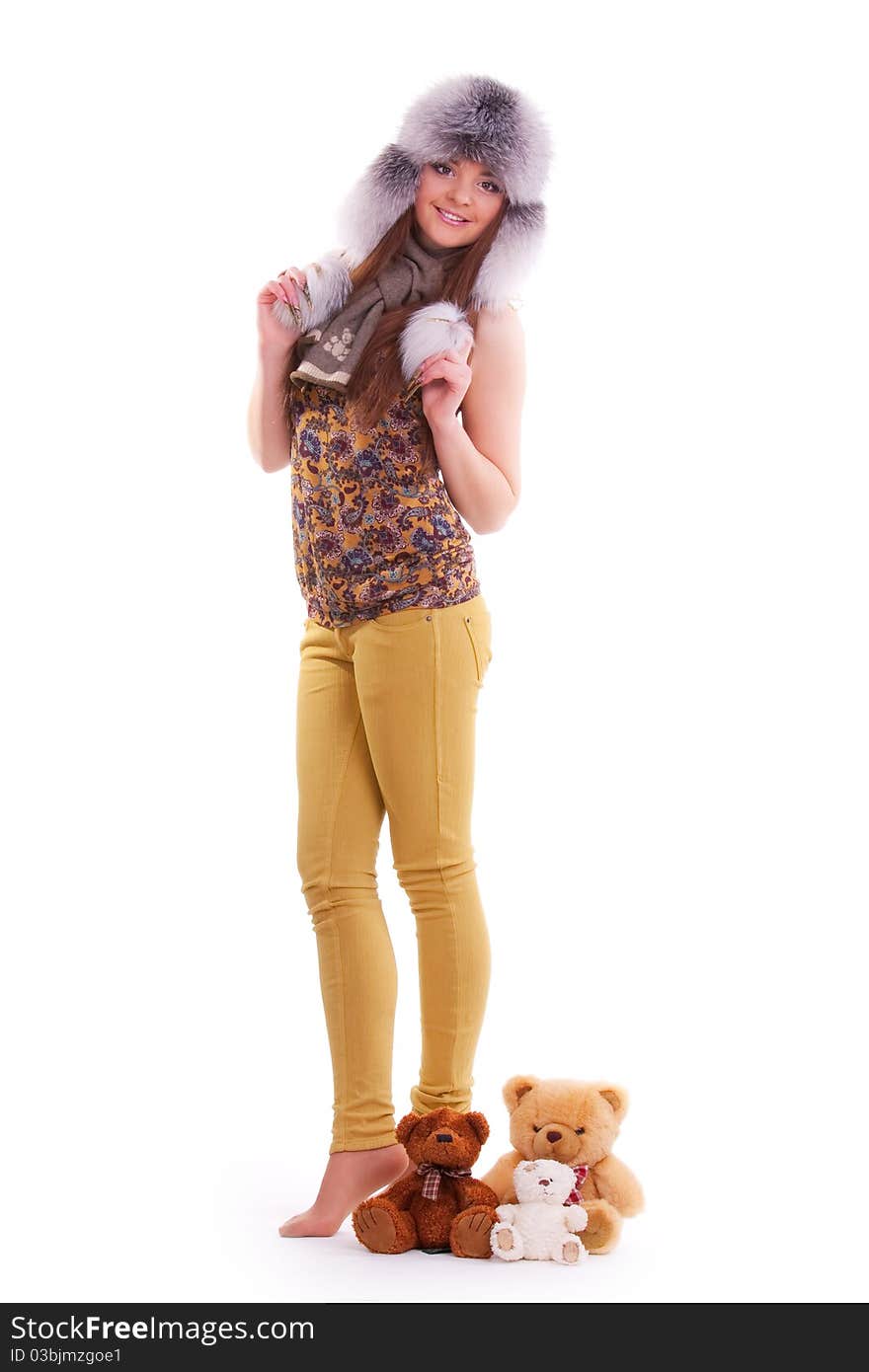 Beautiful brunette in a fur hat standing next to a few teddy bears