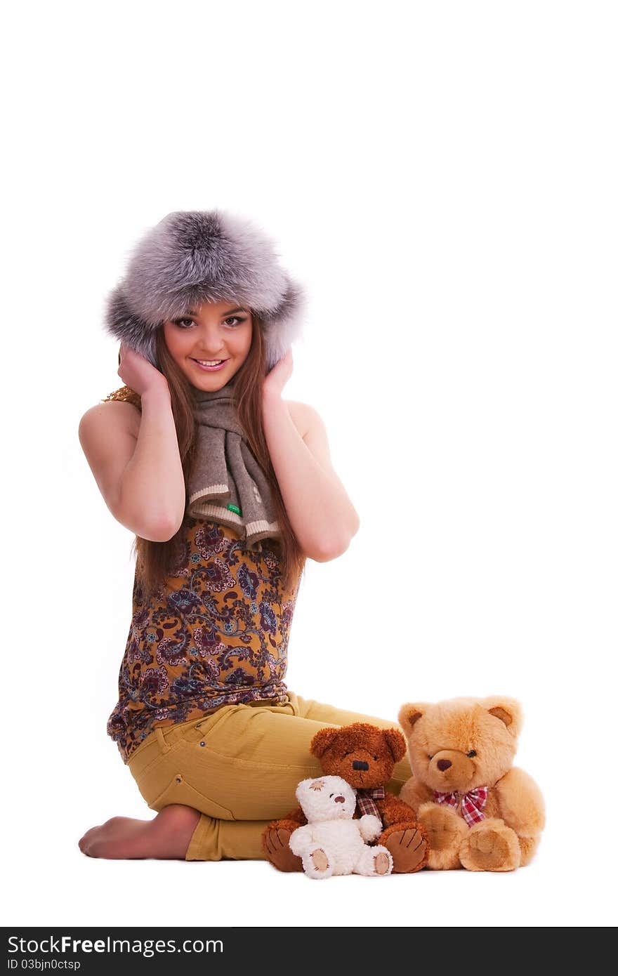 Beautiful brunette in a fur hat sitting next to a few teddy bears