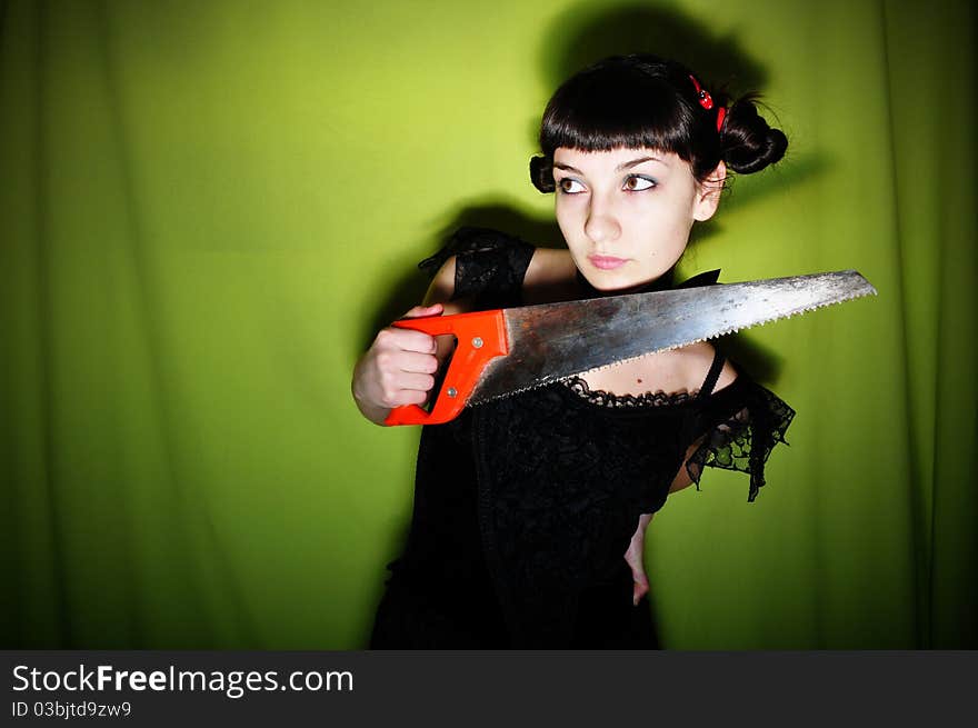 Attractive brunette girl in black dress holding saw. Attractive brunette girl in black dress holding saw