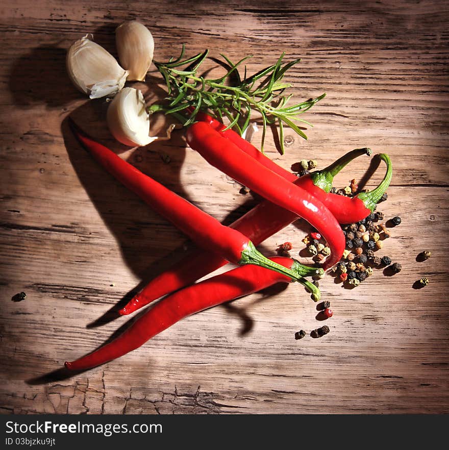 Red hot chili peppers with other spices on wooden background