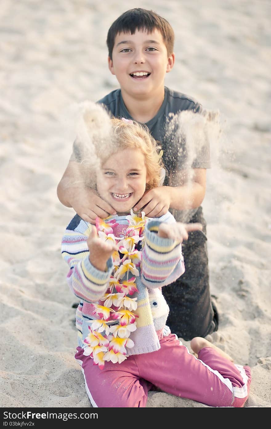 Boy with little girl throwing sand on a beach. Boy with little girl throwing sand on a beach