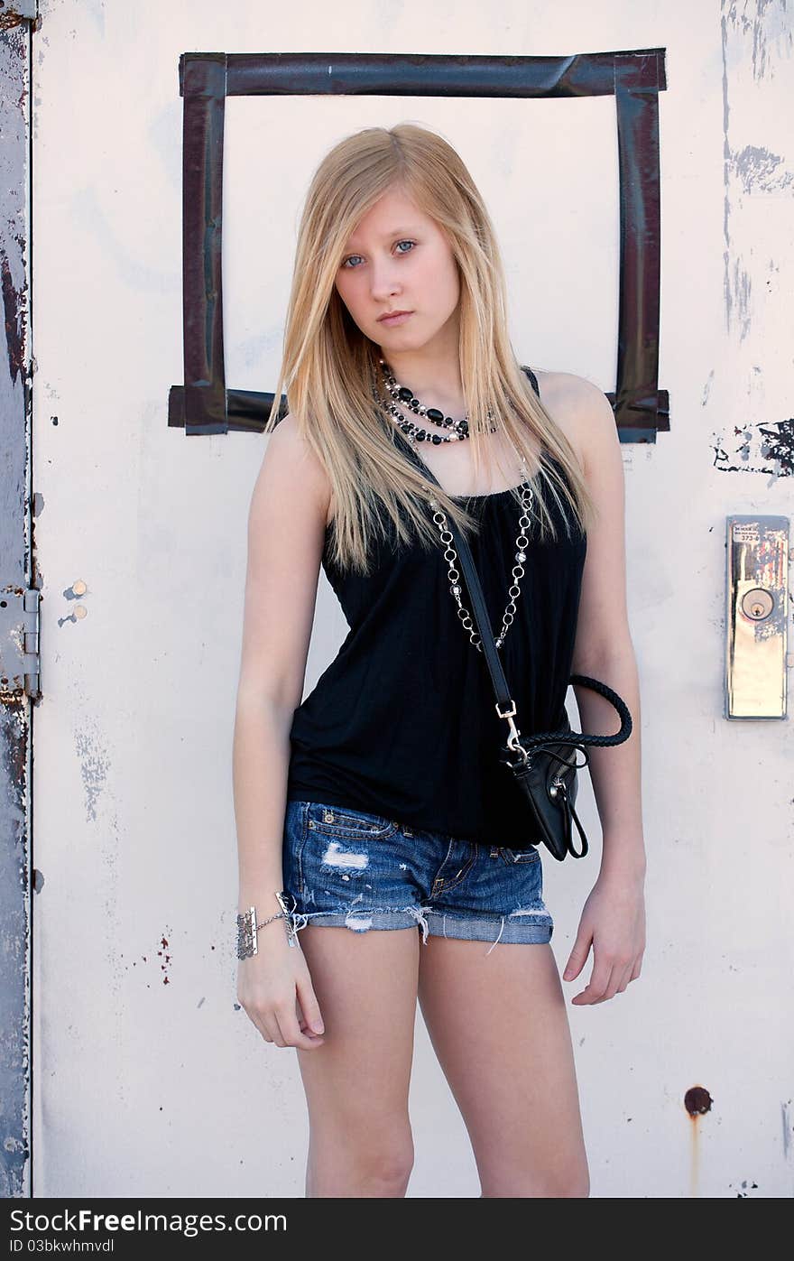 A portrait of a stylish teenager outside, standing in front of an old door. A portrait of a stylish teenager outside, standing in front of an old door.