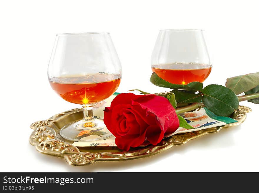 Roses and glasses of brandy on a tray isolated on white background. Roses and glasses of brandy on a tray isolated on white background