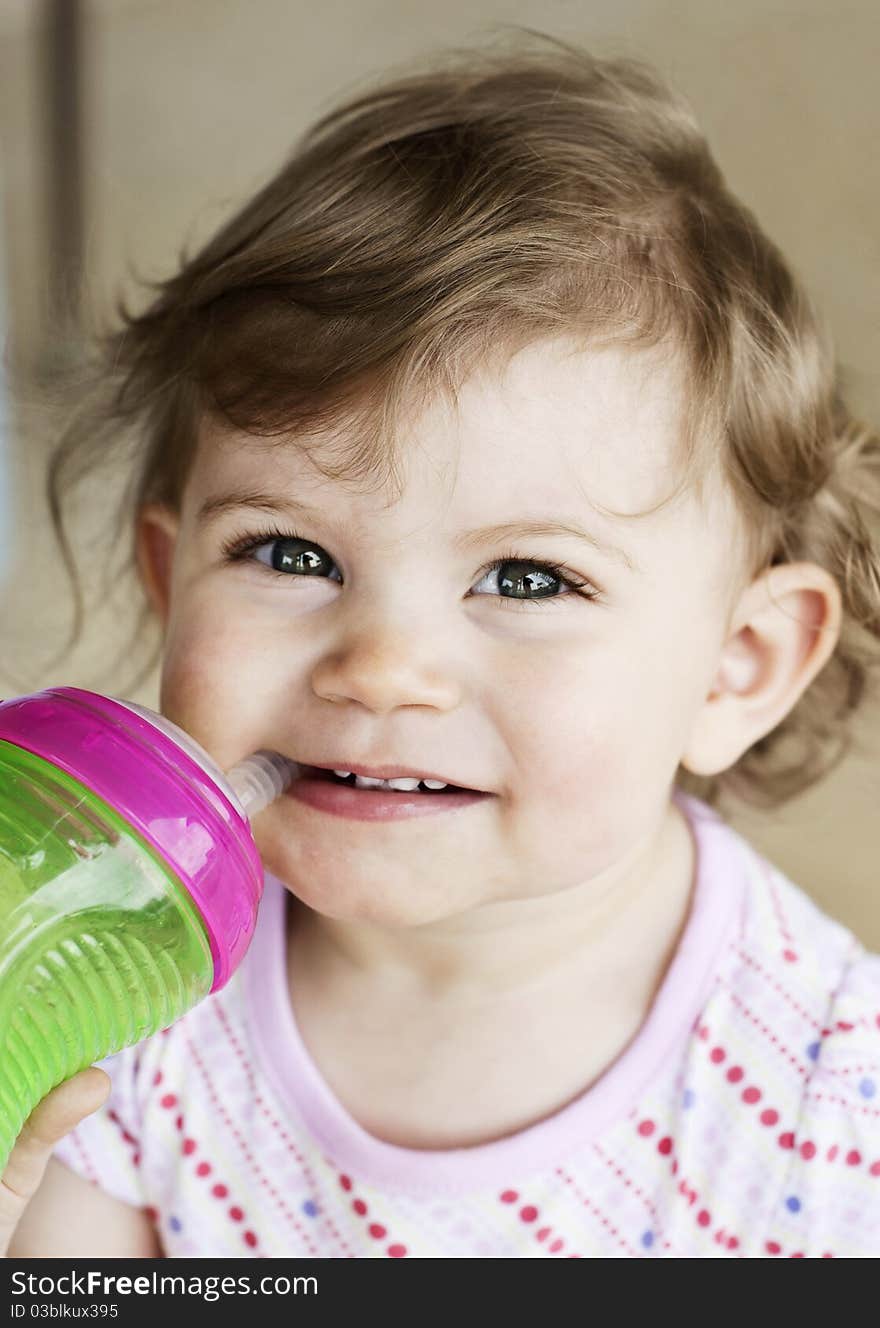 A cute little girl drinking from a sippy cup, selective focus on face. A cute little girl drinking from a sippy cup, selective focus on face