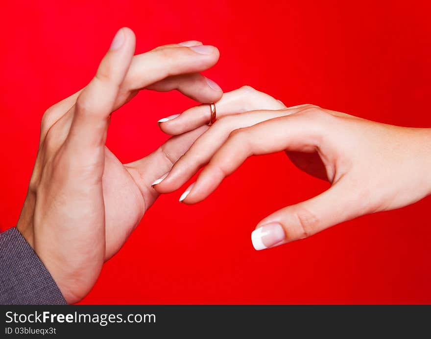 Hands of a bride and a groom, man putting a wedding ring on the finger of his bride