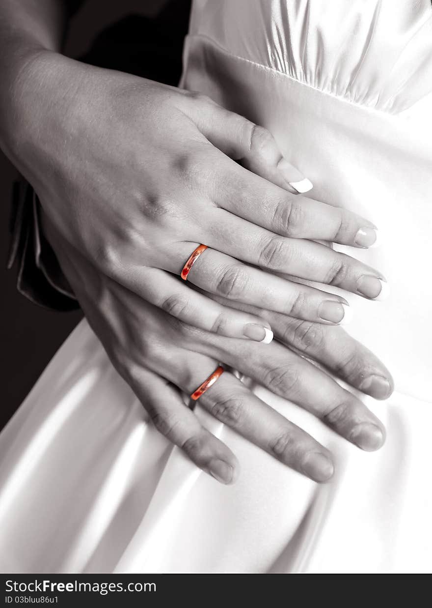 Block and white picture of the hands of a bride and a groom with golden wedding rings (accent on the golden rings)