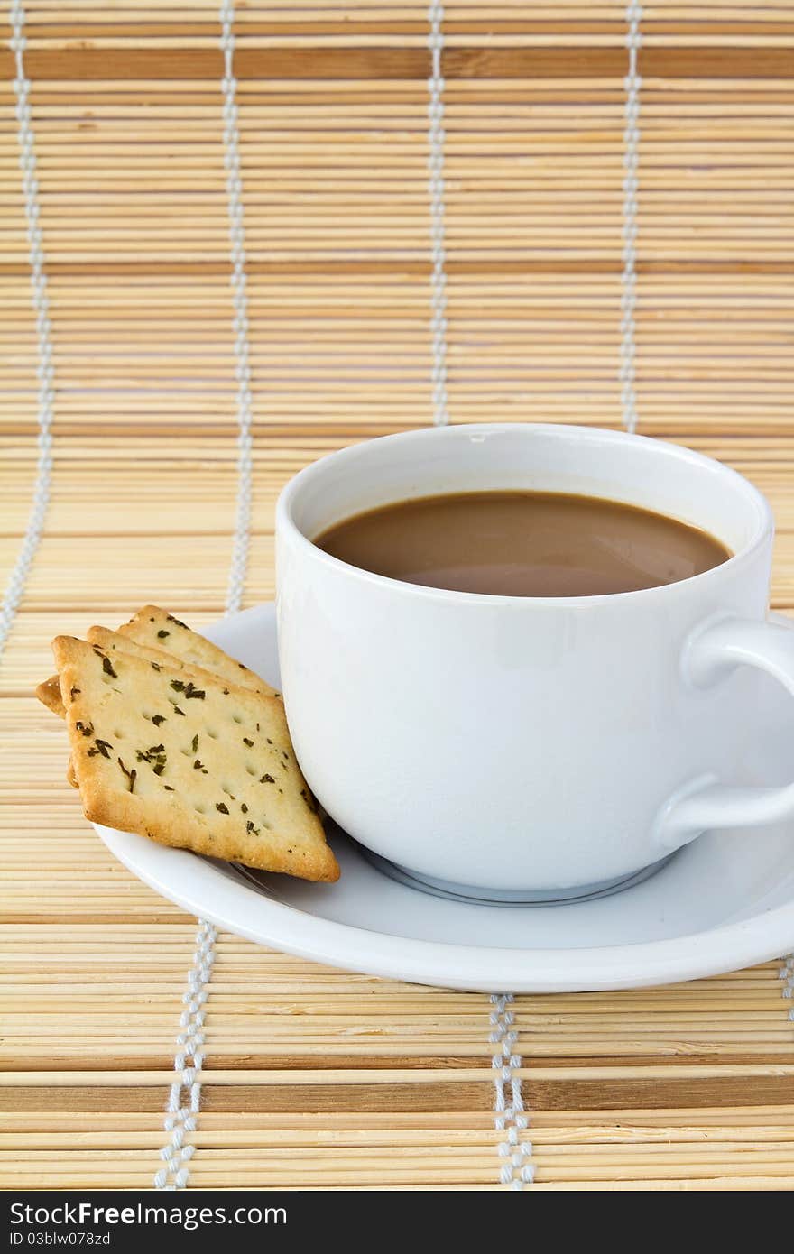 Coffee. White porcelain cup and three biscuit on a mat