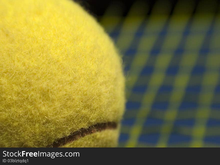 Yellow tennis ball close-up and blurred racket background. Yellow tennis ball close-up and blurred racket background.