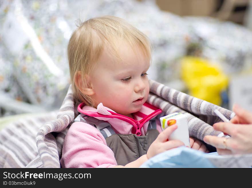 Adorable baby sit in shopping cart with small pack of juice give by mother. Adorable baby sit in shopping cart with small pack of juice give by mother