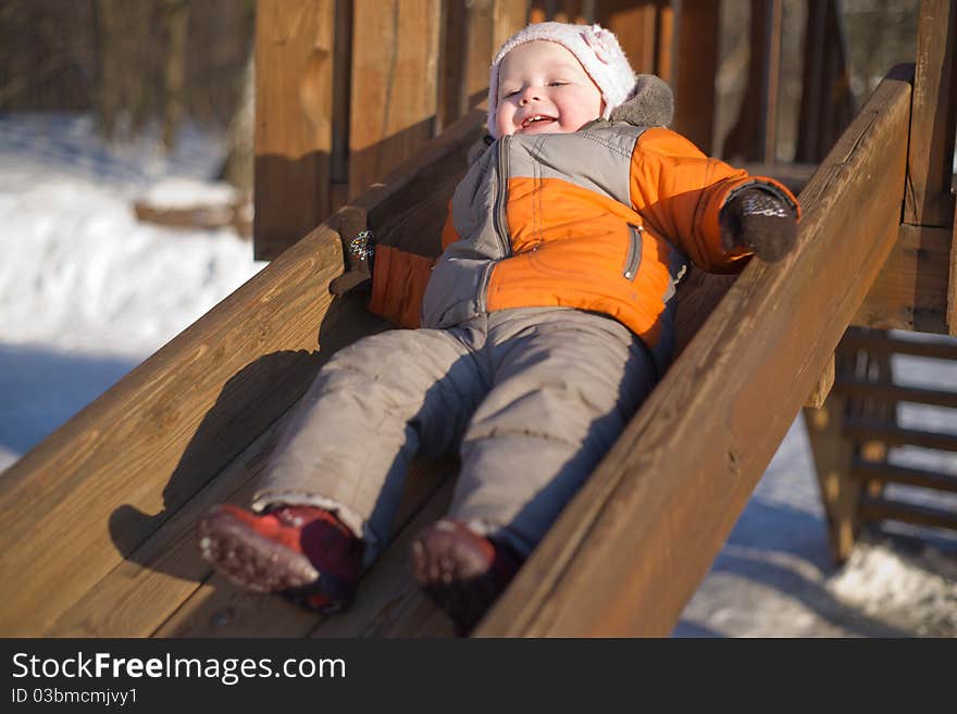 Adorable baby sliding from wood slide in park