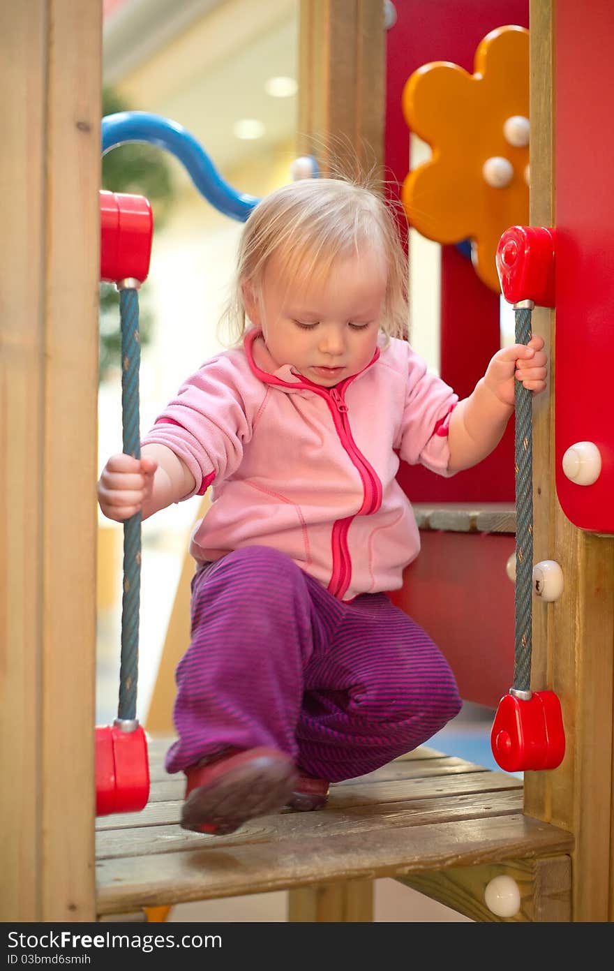 Young adorable baby climb to baby slide on playground in mall