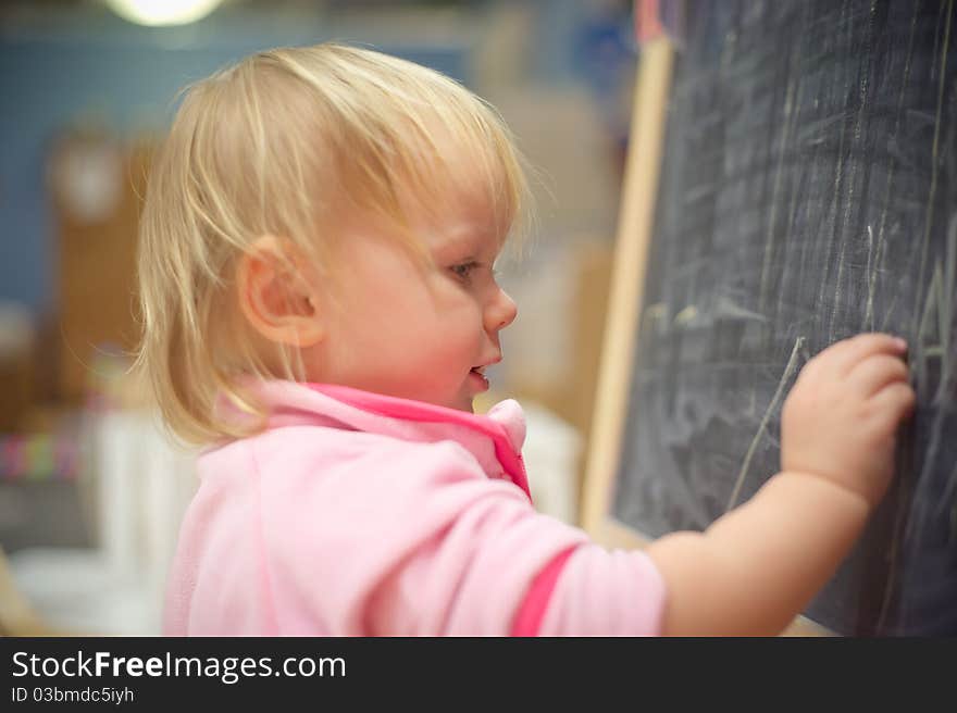 Adorable baby draw on blackboard with chalk