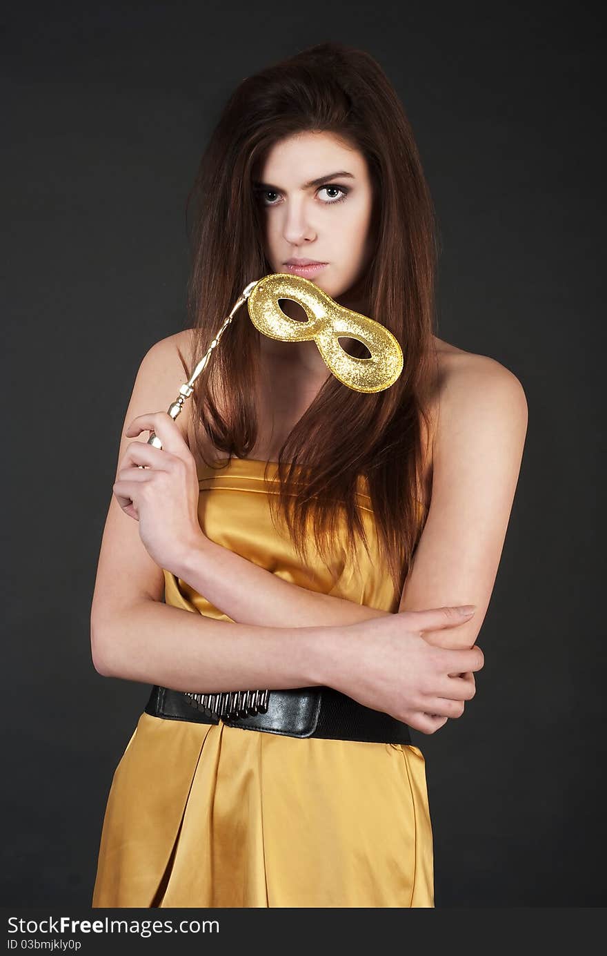 Beautiful young woman holding a carnival mask wearing against black background