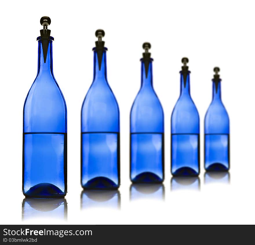 Five blue glass bottles with water on a white background