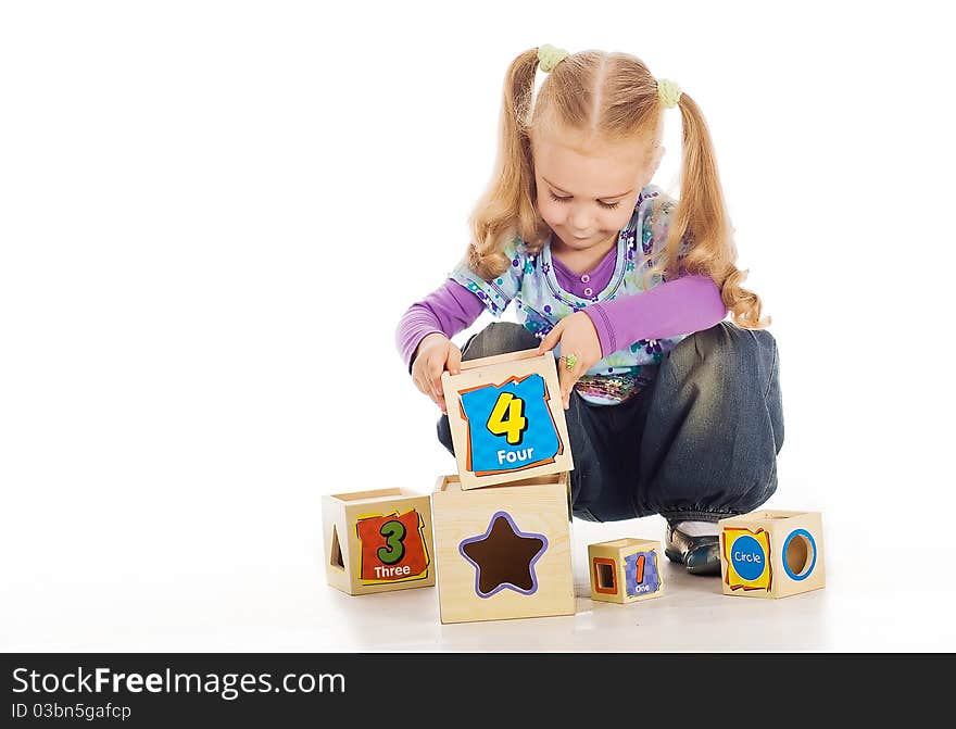 The small lovely girl collects toy cubes. 4 years old.