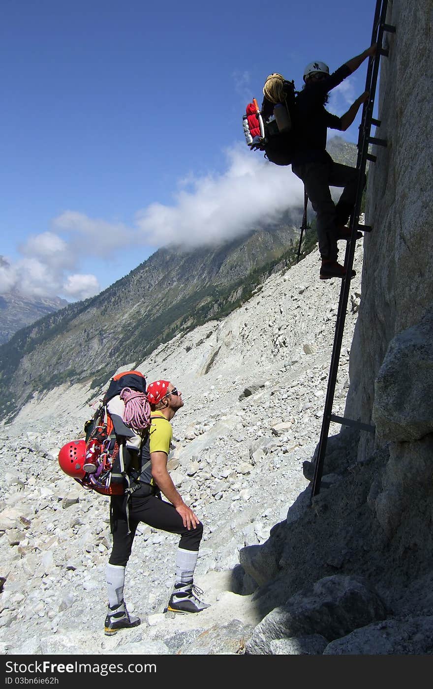 Climbers using a steel ladder to climb from the Mer De Glace morraine towards the Charpoua hut, in the Alps, near Chamonix, Mont Blanc region, France. Climbers using a steel ladder to climb from the Mer De Glace morraine towards the Charpoua hut, in the Alps, near Chamonix, Mont Blanc region, France