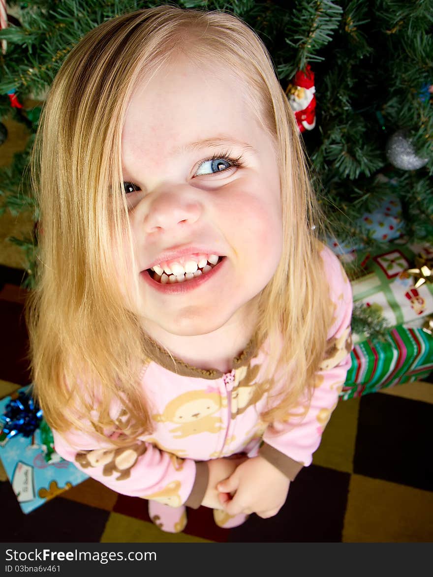 Funny picture of a child standing in front of a christmas tree with presents smiling. Funny picture of a child standing in front of a christmas tree with presents smiling.