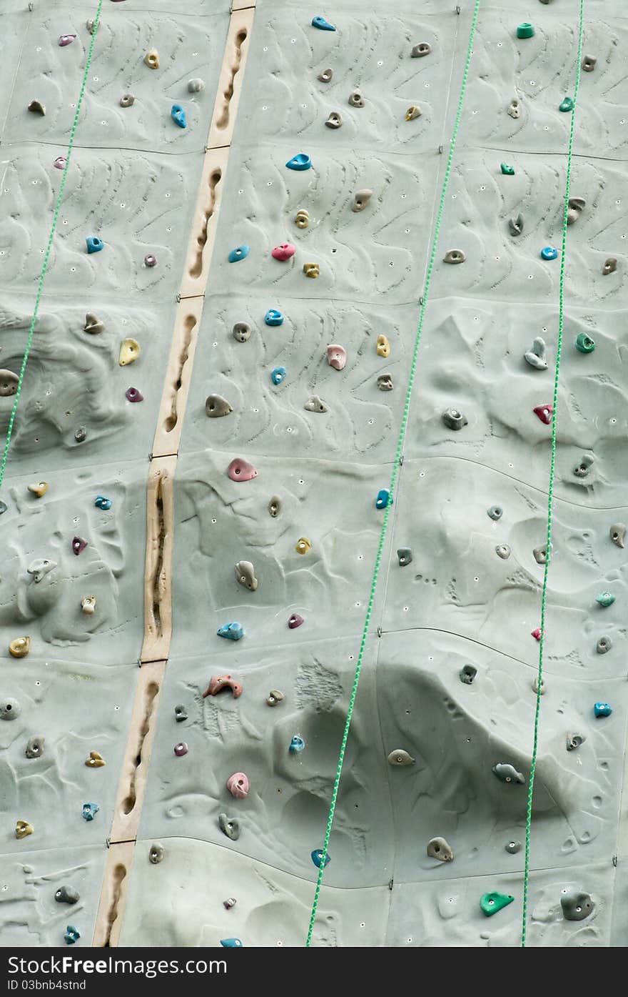 A portrait of climbing wall with hand grips and ropes