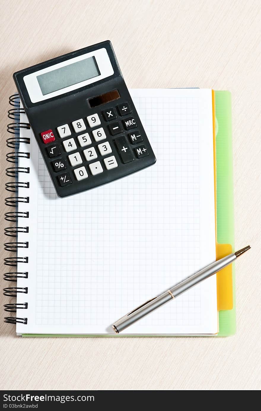 Notebook, silver ballpen and calculator on wooden desk. Notebook, silver ballpen and calculator on wooden desk