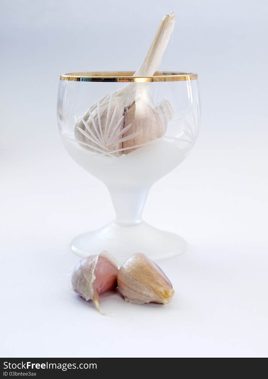 Head and the cloves of garlic in the glass isolated on white