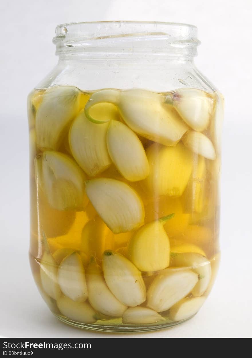 Cloves of garlic in the pot with sunflower oil isolated on white