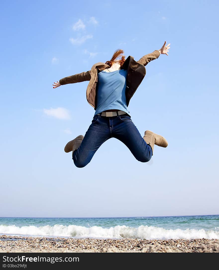 Young beautiful girl jumping at the beach.