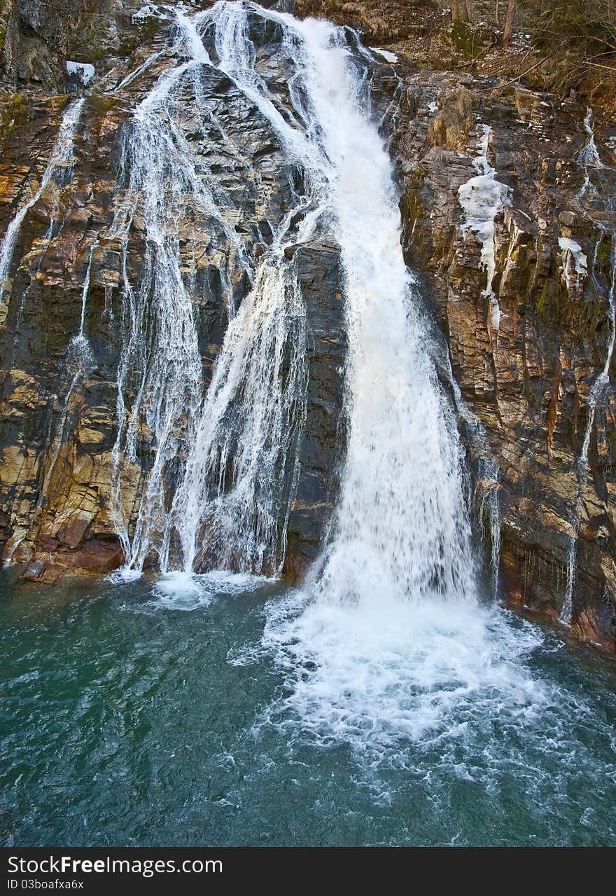 Mountain waterfall on a rock and blue lake