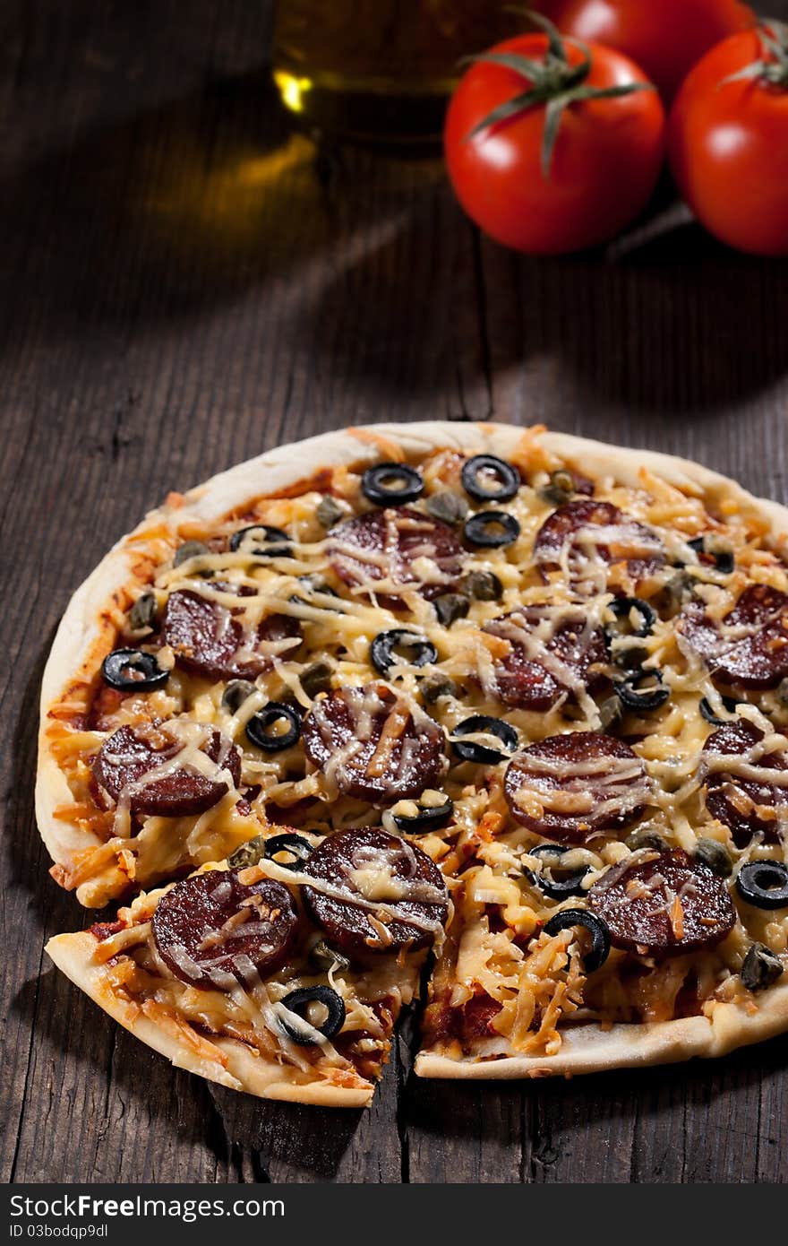 Homemade pizza with salami, cheese and black olives.