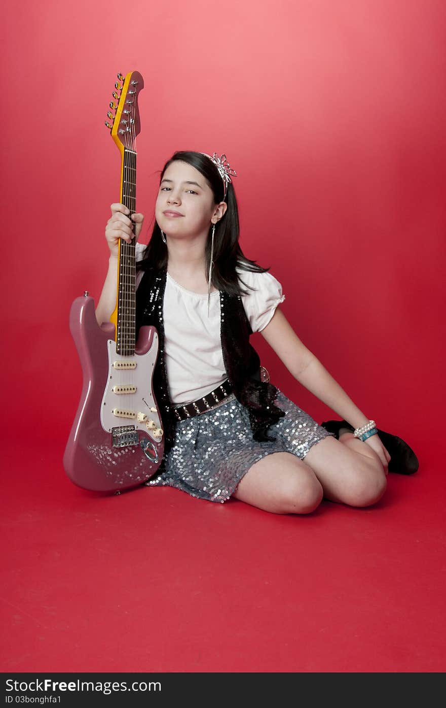 Young girl sitting holding electric guitar. Young girl sitting holding electric guitar