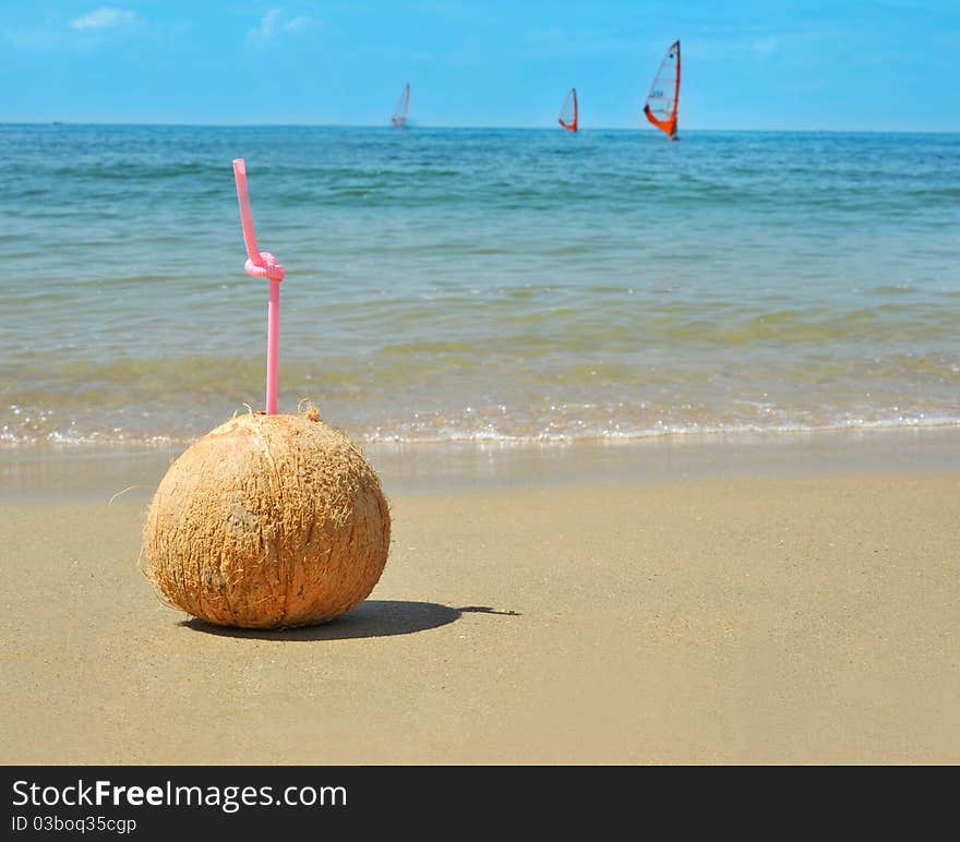 Coconut drink on the sand with sea in background