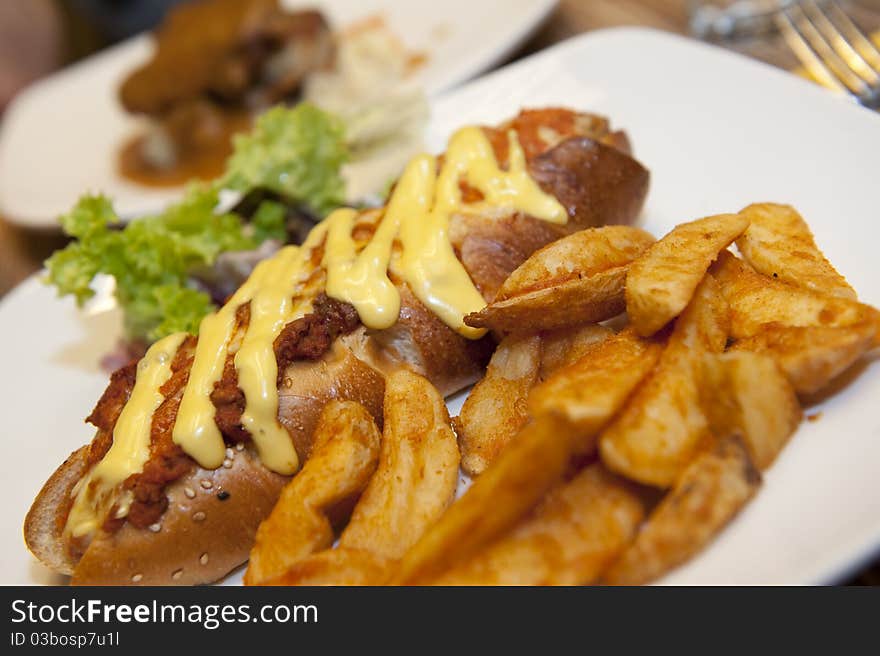 A plate of delicious sausage bread served with cheese and bolognese, accompanied by potato wedges and garnished, ready to be served!. A plate of delicious sausage bread served with cheese and bolognese, accompanied by potato wedges and garnished, ready to be served!