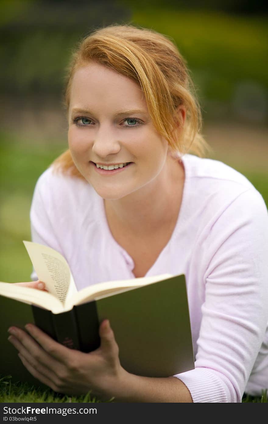 Young woman sitting outside reading. Young woman sitting outside reading