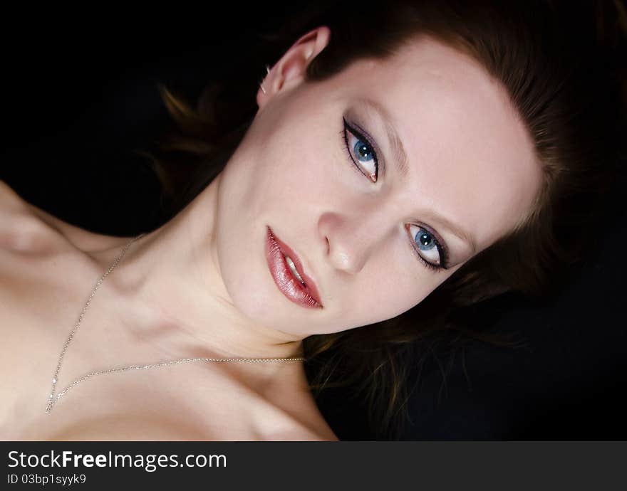 Young woman with necklace on dark background