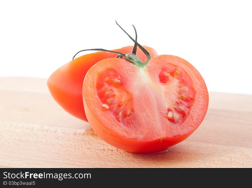 Two part of tomato on brown kitchen board. Horizontal image