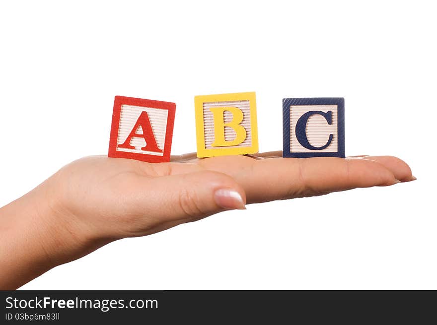 The hand holds a cube with letters on white