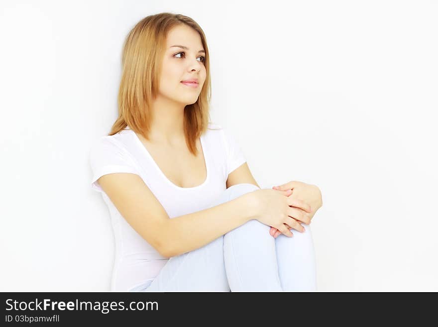 Pretty young lady sitting on the floor on light background