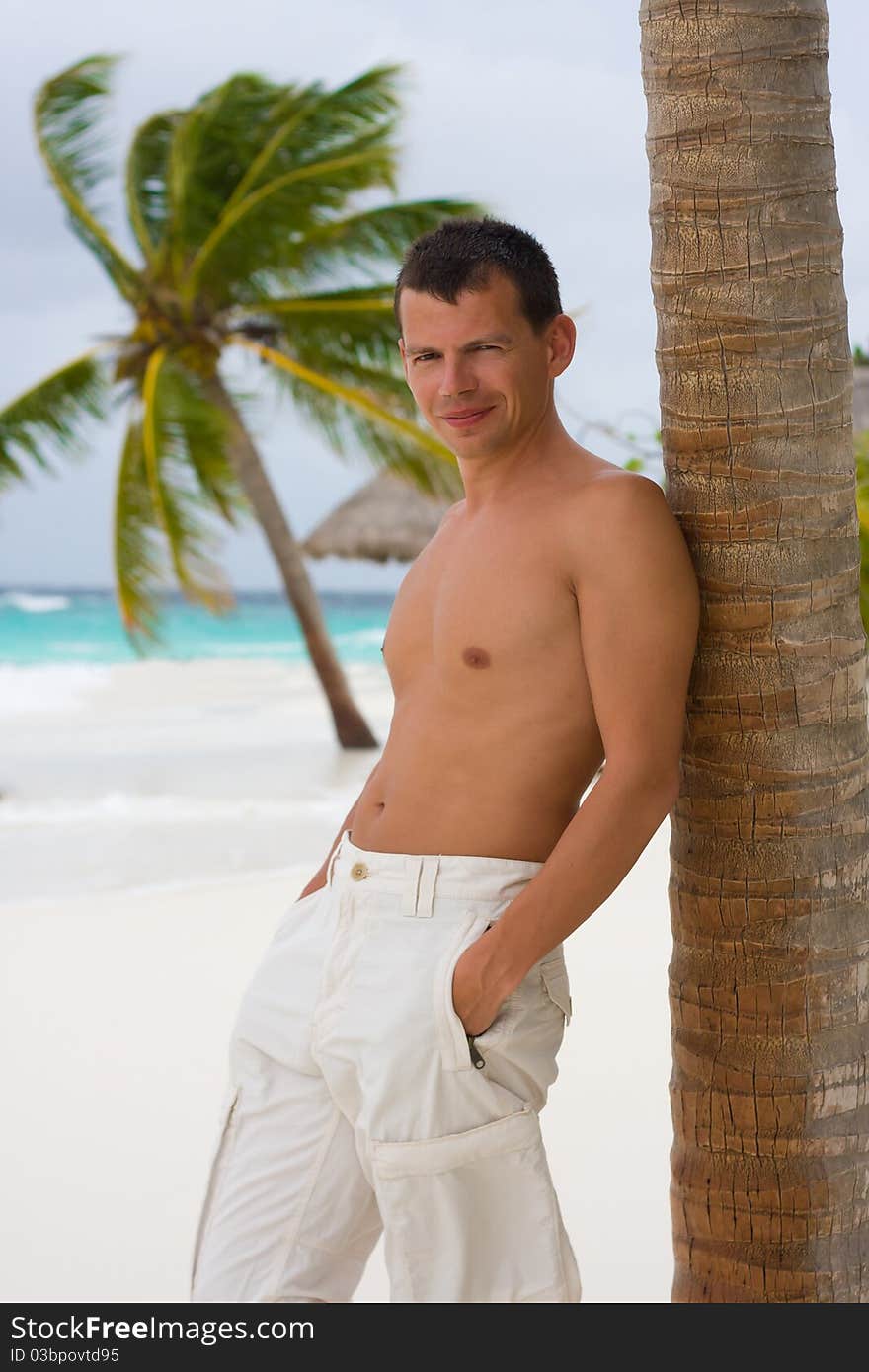 Young man on a tropical beach in the morning during a gale