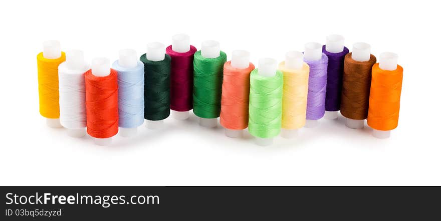 Spools multi-colored threads located a wave isolated on a white background