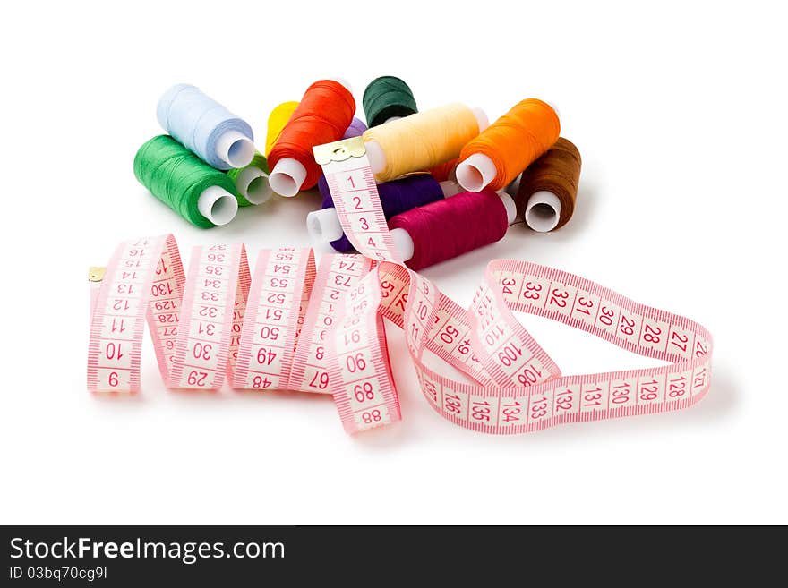 Spools Multi-colored threads randomly with a measuring tape of the tailor isolated on a white background. Spools Multi-colored threads randomly with a measuring tape of the tailor isolated on a white background